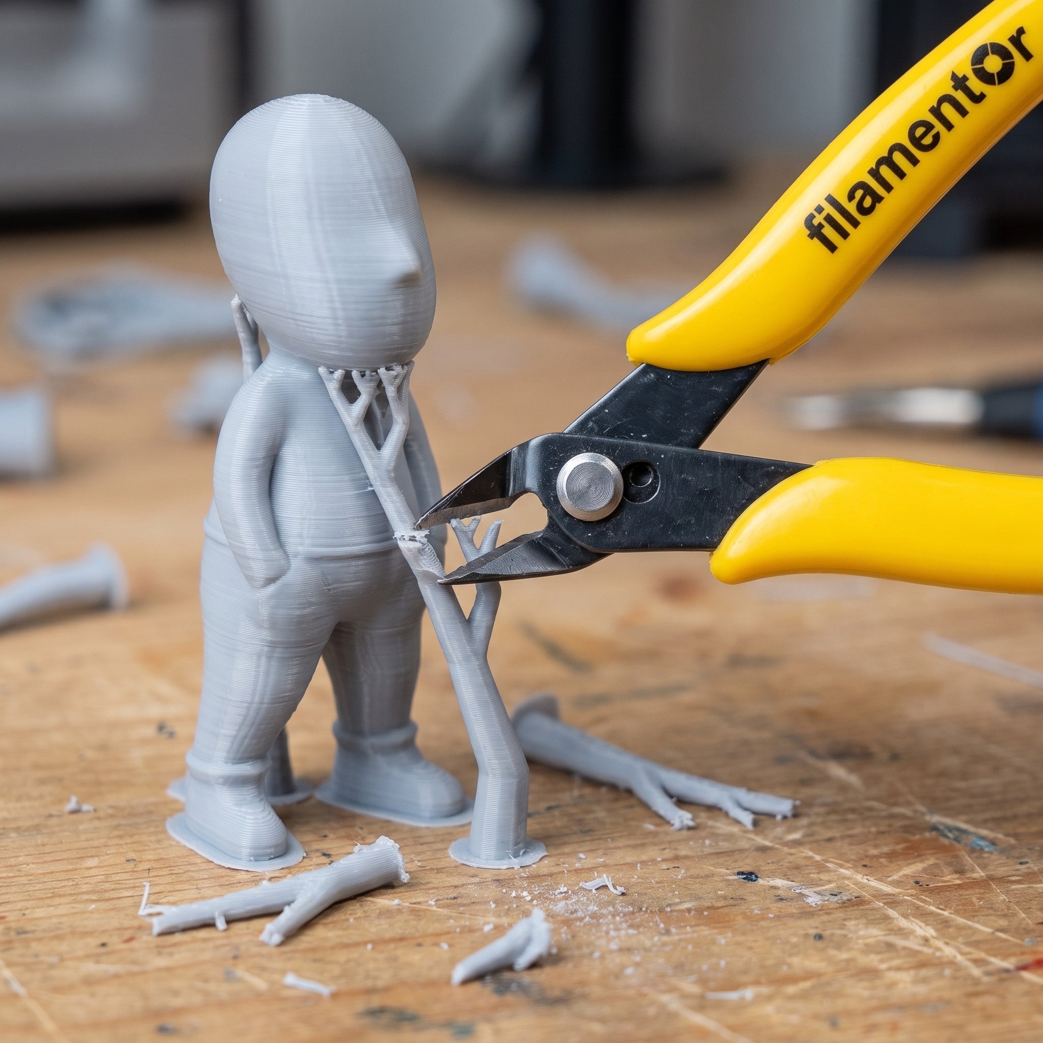 Clește de tăiat Filamentor îndepărtând suporturile de pe o piesă gri imprimată 3D